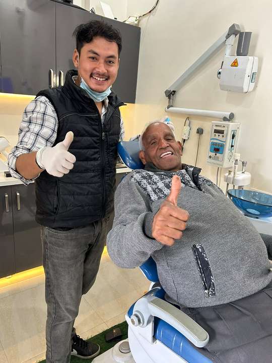 An elderly patient giving a thumbs-up after treatment